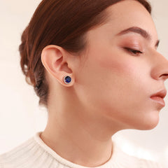 Close up of Azuline Halo platinum-plated stud earrings with a dark blue centerpiece and radiant halo accents