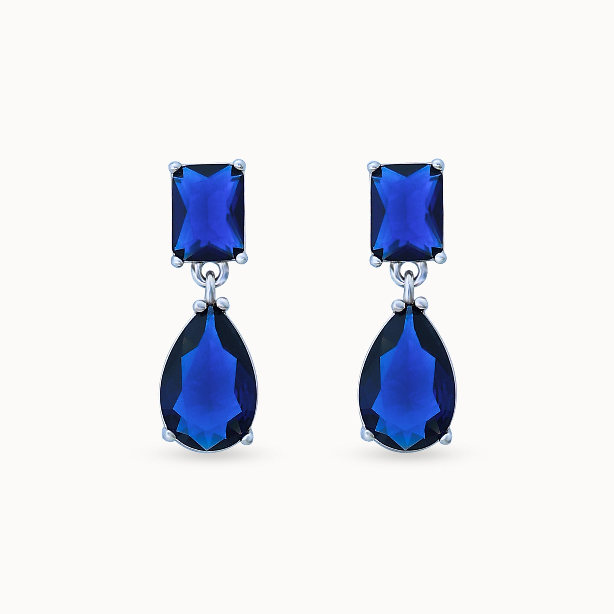 Product Close up of Azura Glow Drops, platinum-plated earrings with dark blue sapphire-like stones for an elegant, minimalistic look